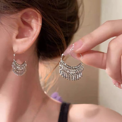 Silver water drop tassel earring worn, with hand holding the other earring, showcasing the stylish, dangling water drop look