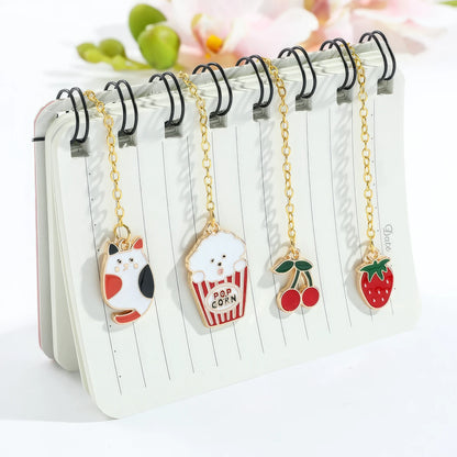 Multiple animal and plant themed bookmarks with golden chains, displayed on notebook, light background