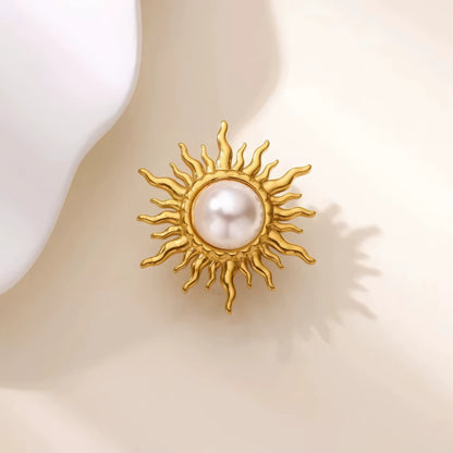 Baroque flame sun brooch with pearl, placed on light surface, showcasing golden rays
