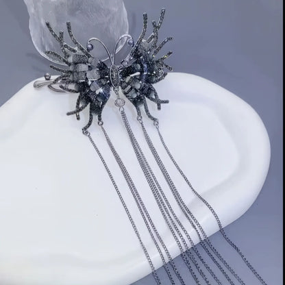Black butterfly tassel twist clip displayed on a white plate, light background