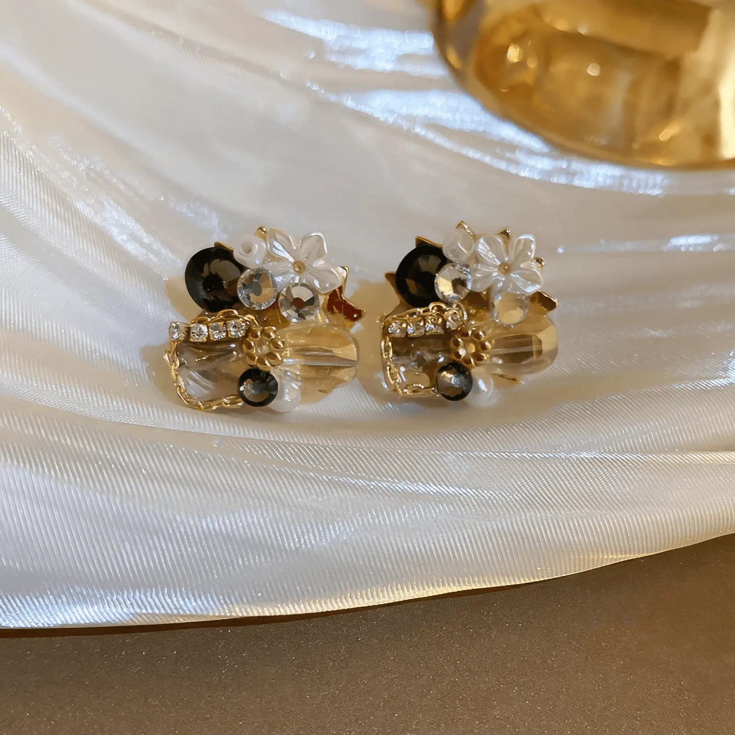 Black and gold crystal butterfly earrings on a white plate