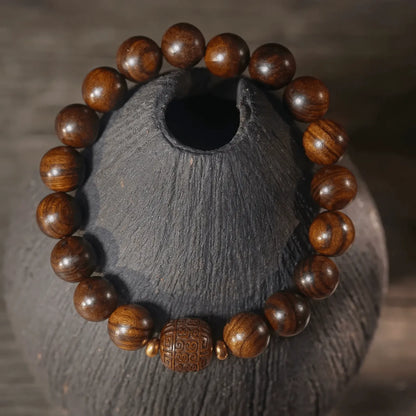 Black rosewood cloud - pattern bracelet placed on gray vase, highlighting natural wood texture