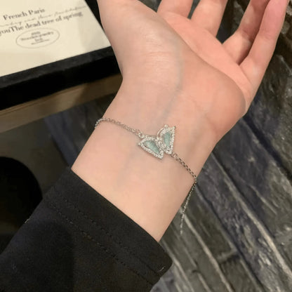Hand wearing a blue butterfly - shaped silver bracelet