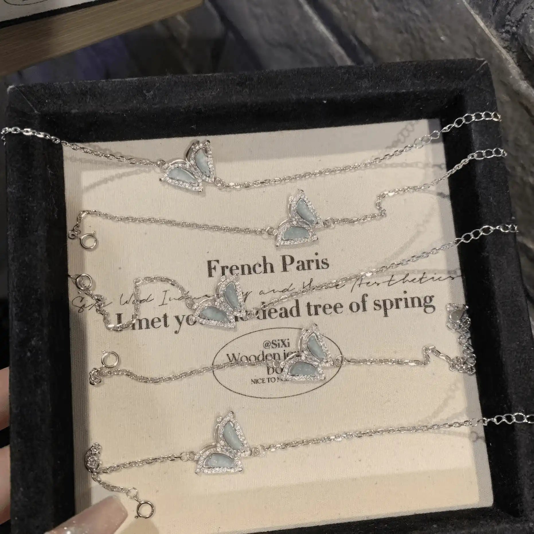 Blue butterfly - shaped silver bracelets in a black box with “French Paris” text