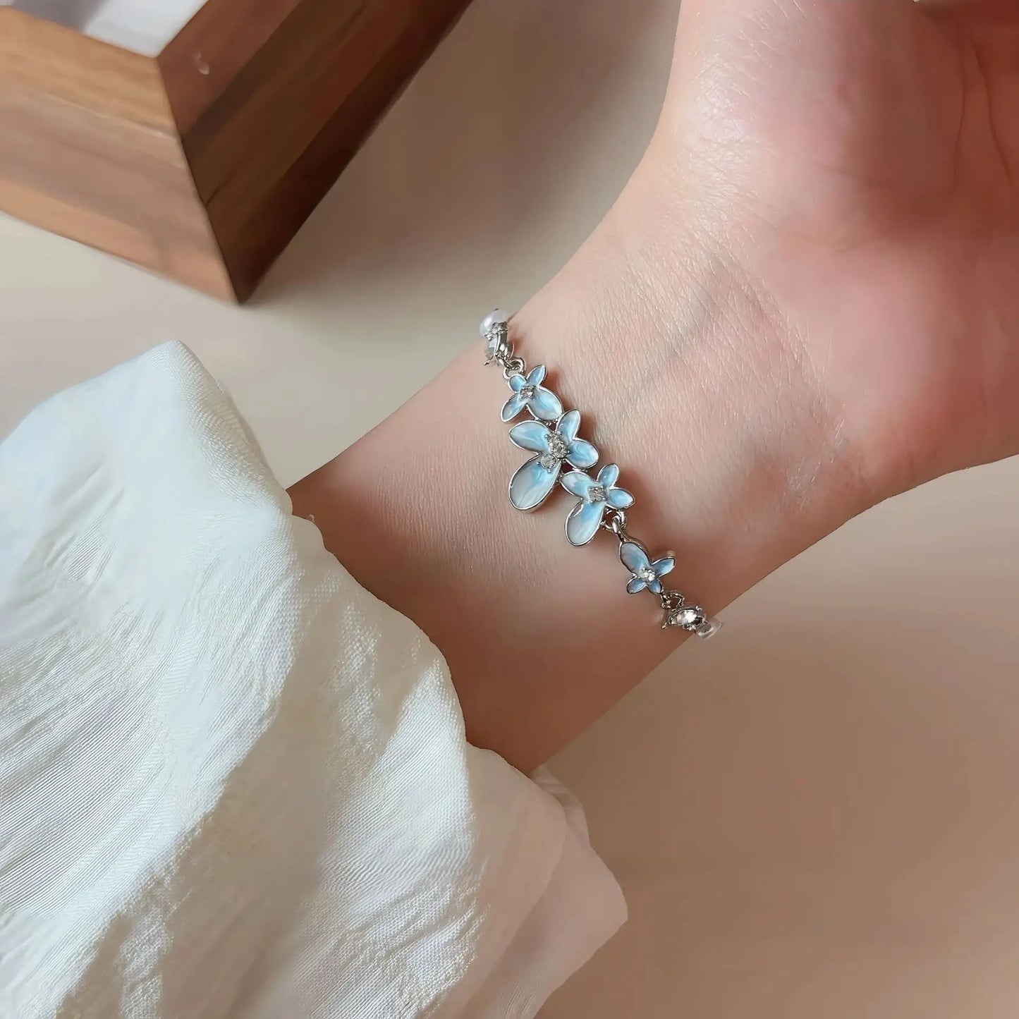 Blue butterfly glaze bracelet worn on a wrist, with a white fabric sleeve visible
