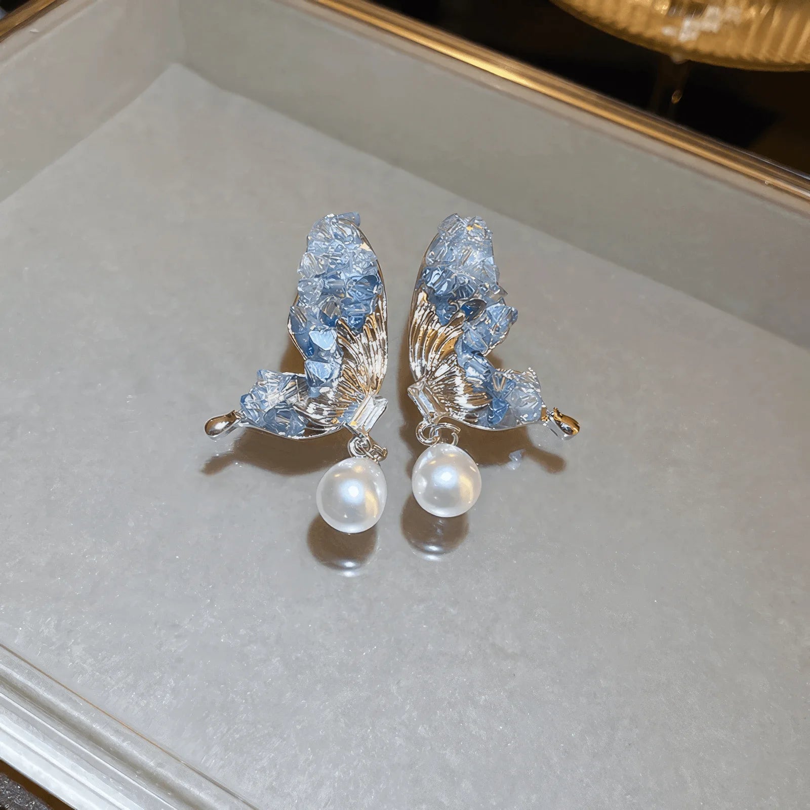 Blue crystal butterfly earrings placed on a display tray
