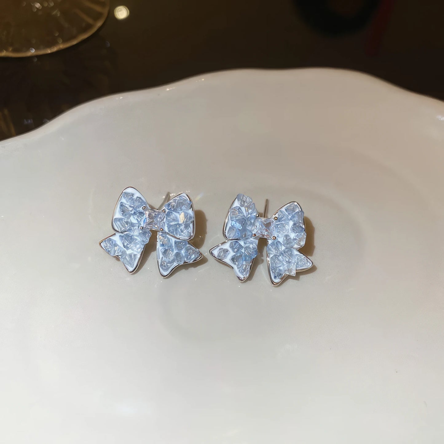 Blue crystal butterfly earrings on a white plate