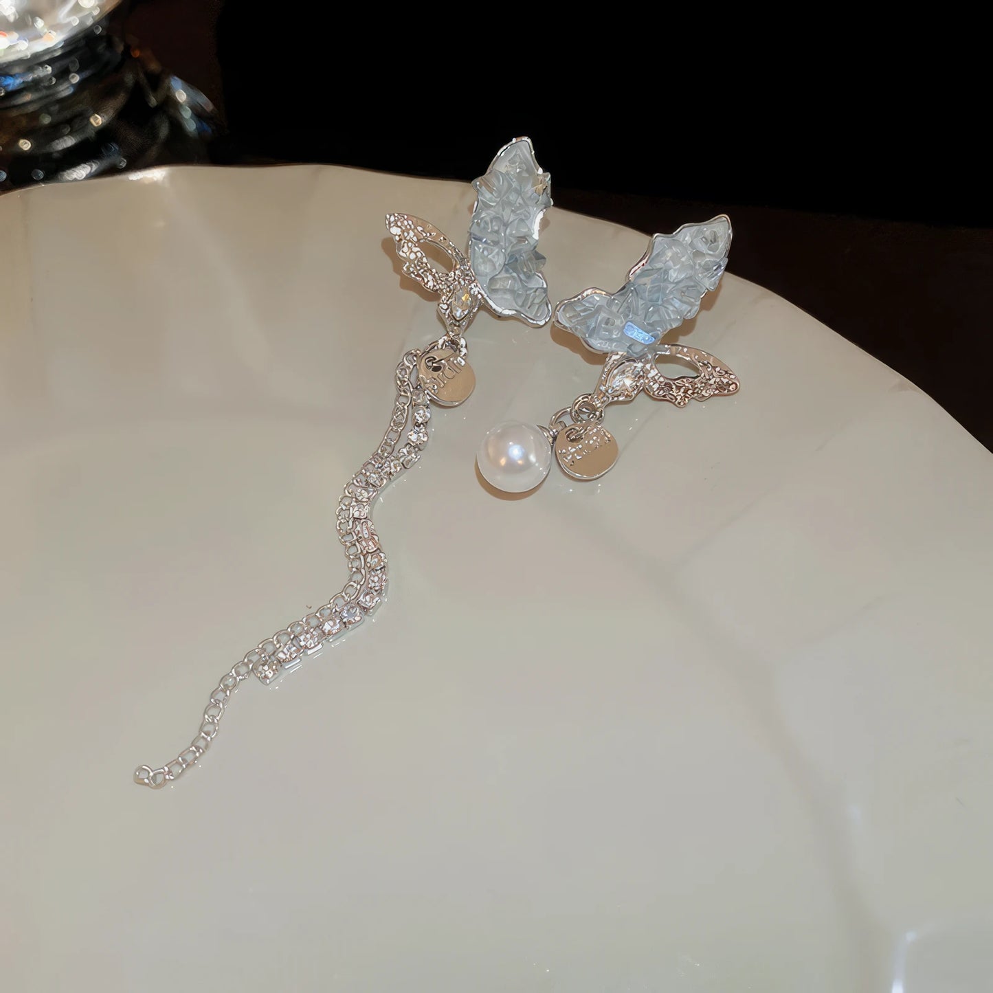 Blue crystal butterfly earrings with chain on a surface