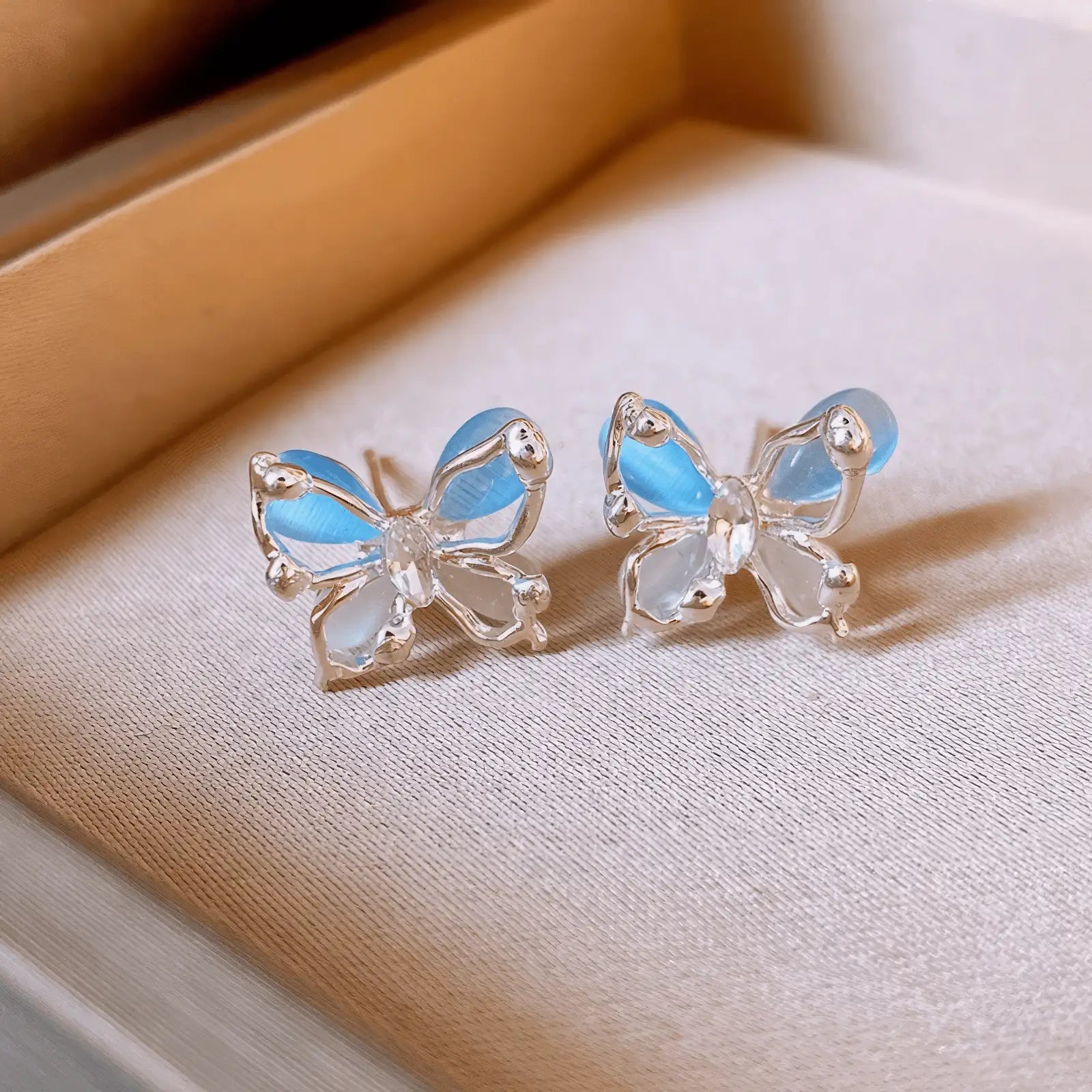 Blue crystal butterfly earrings with iridescent effect on a display tray