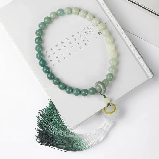 Bodhi lotus tassel prayer beads with gradient green tassel, placed on book with text