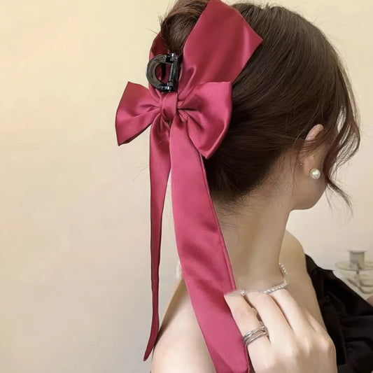 Red bow hair claw worn in updo, side view of model