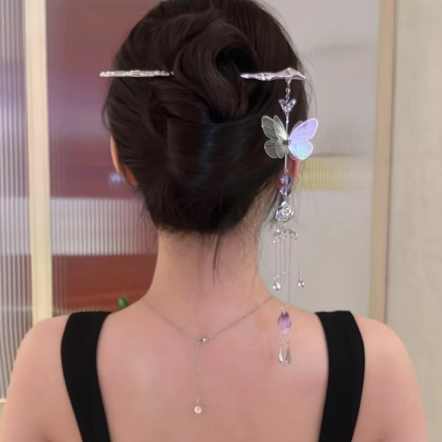 Silver butterfly amethyst tassel hairpin worn in an updo hairstyle, black clothing background