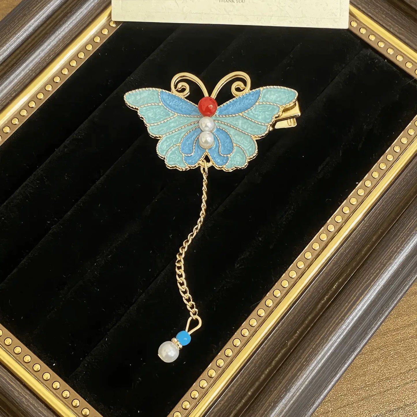 Butterfly and flower hair clip set, blue - and - gold - colored with pearl decorations, in a framed showcase