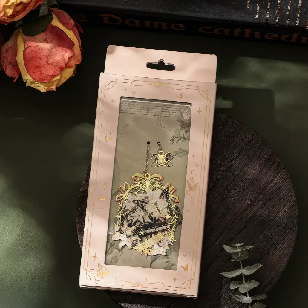 Close - up view of a butterfly - shaped metal lattice bookmark, highlighting its intricate design, on a table with a small flower, realistic product display style, 3:4 ratio