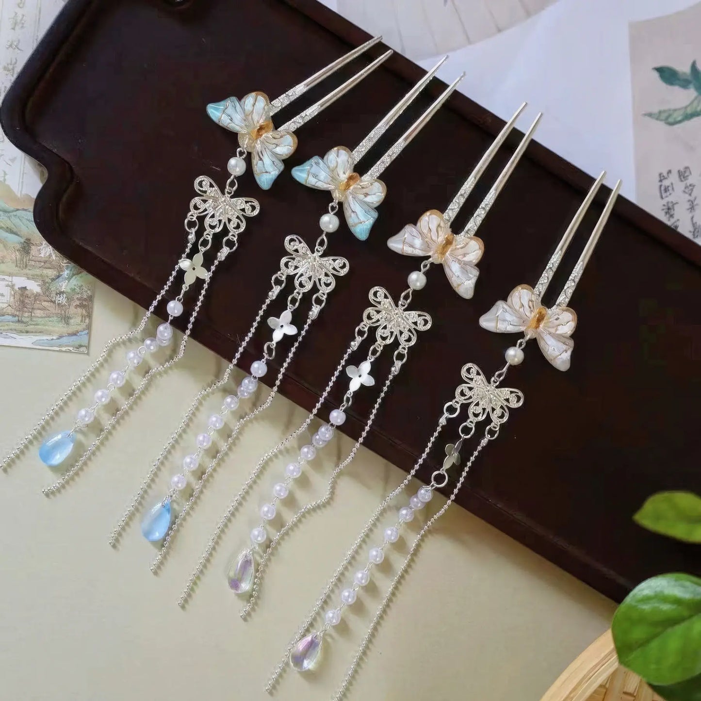 Another set of butterfly pearl small U - hairpin tassels displayed on a wooden tray