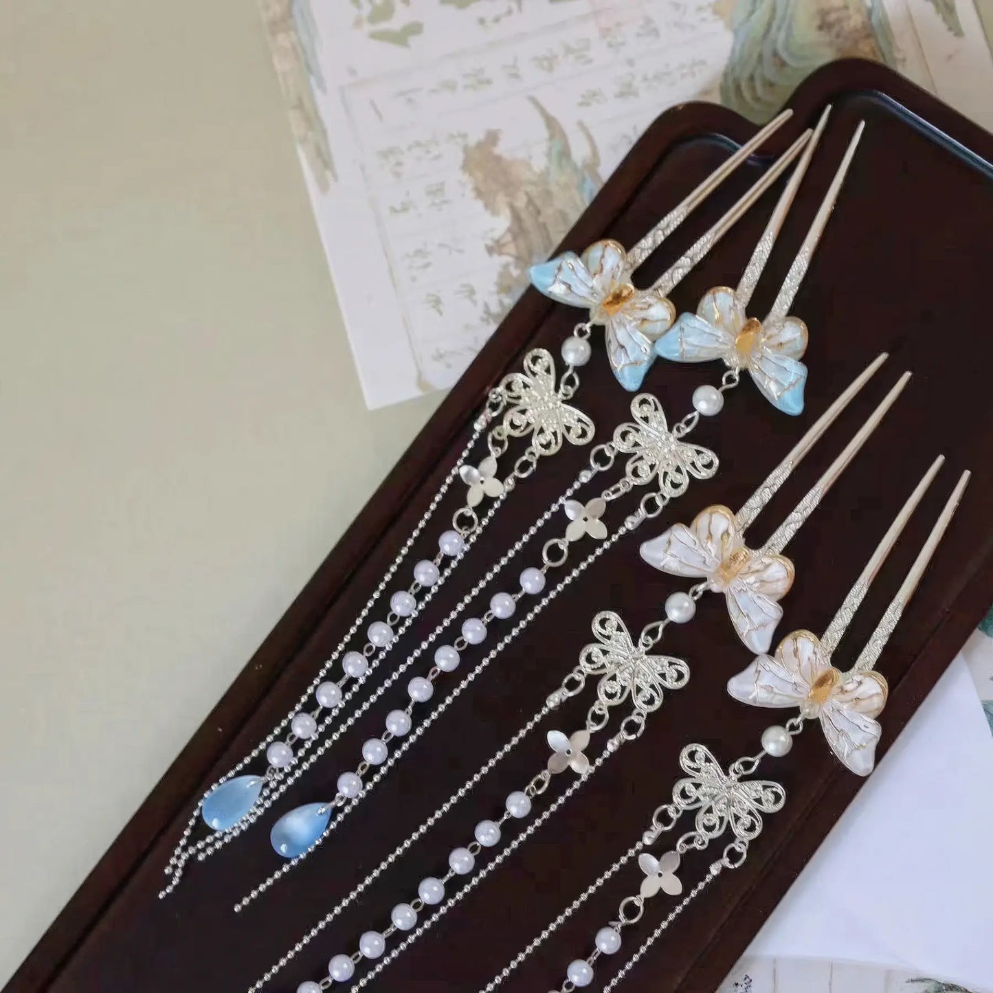 Set of butterfly pearl small U - hairpin tassels displayed on a wooden tray