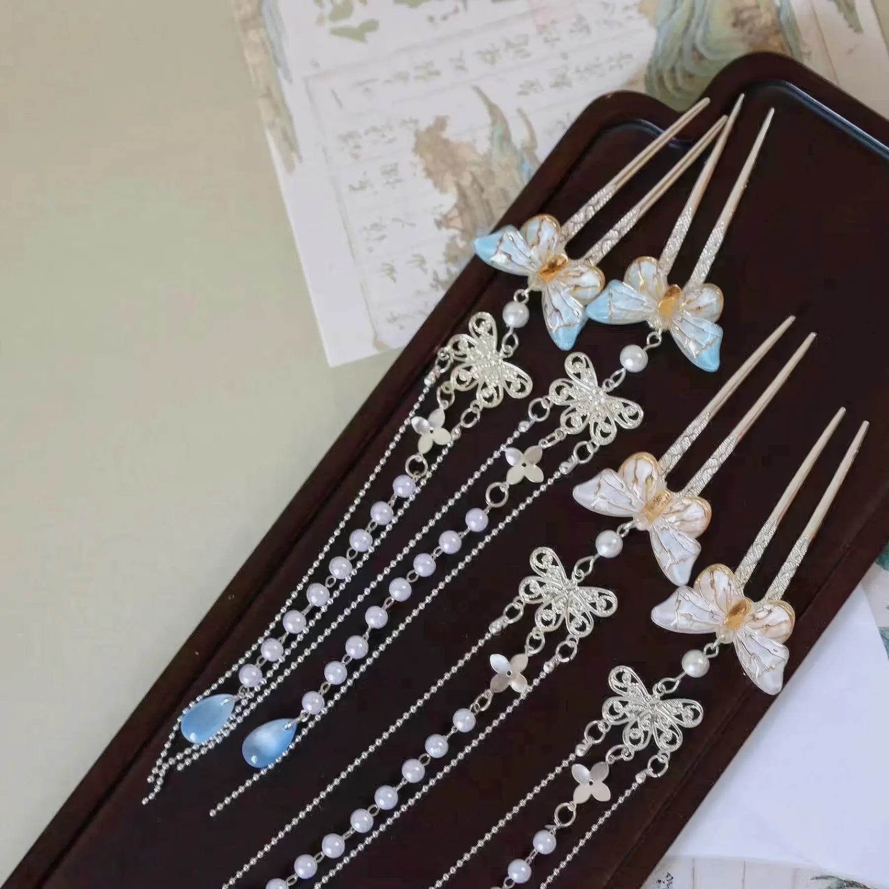 Set of butterfly pearl small U - hairpin tassels displayed on a wooden tray