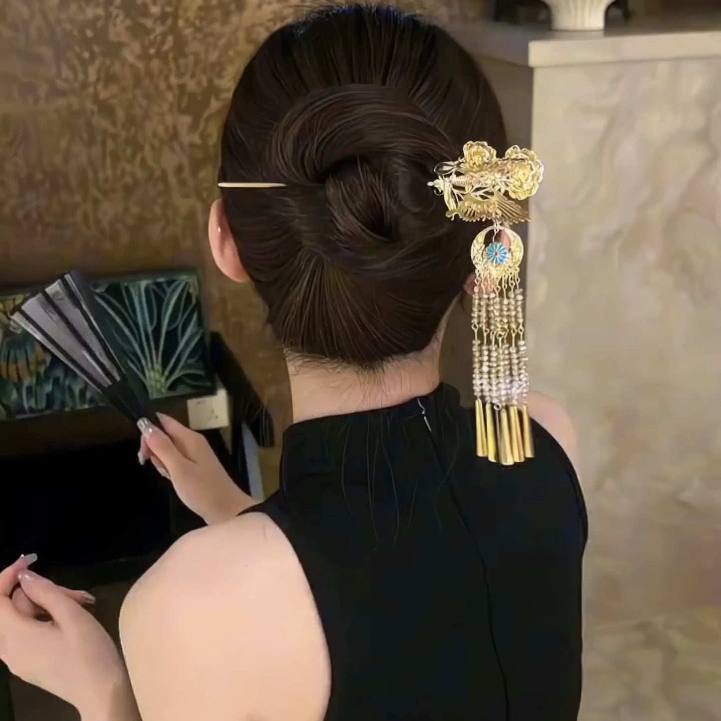 Butterfly-peony tassel hairpin worn in updo hairstyle with black outfit, side-back view