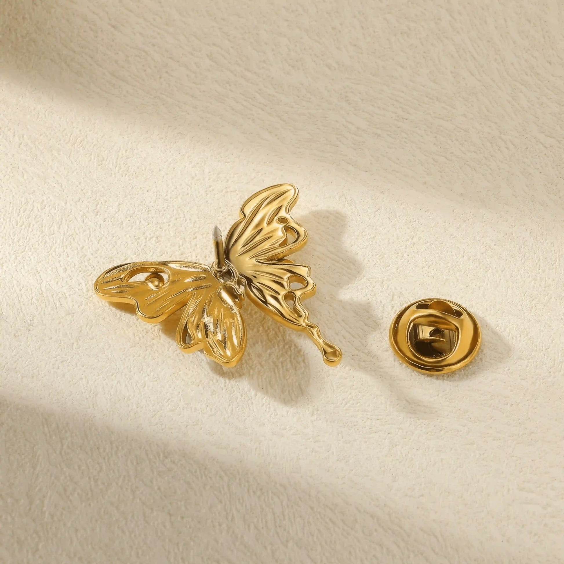 Back view of titanium steel butterfly brooch, showing pin mechanism, isolated on beige surface