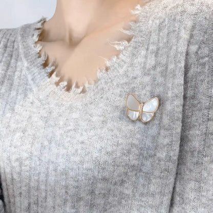Another angle of white butterfly brooch worn on gray sweater, emphasizing charm