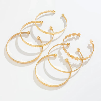 Set of gold carved pattern flower bangles, isolated on white background