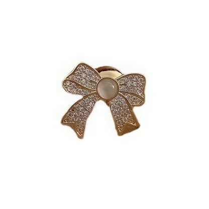 Cat - eye stone brooch with bow design, gold and diamond - like accents, isolated on white