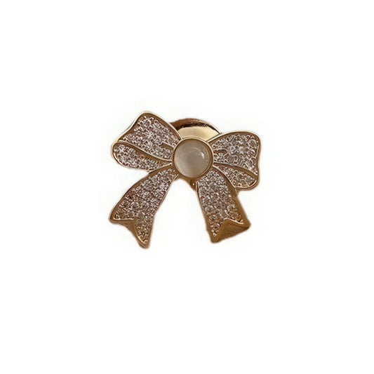 Cat - eye stone brooch with bow design, gold and diamond - like accents, isolated on white