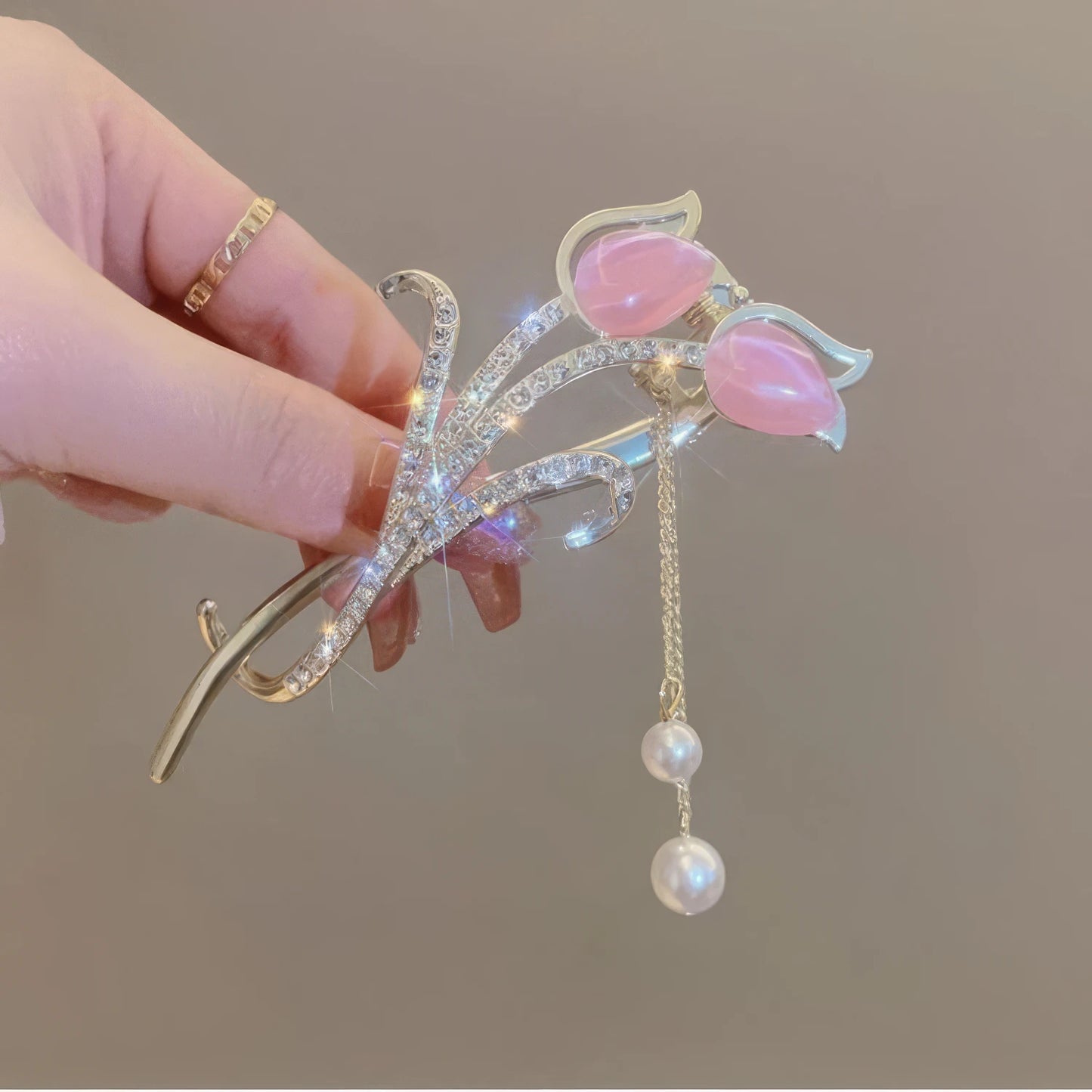 Hand holding pink cat - eye stone tulip tassel hair clip