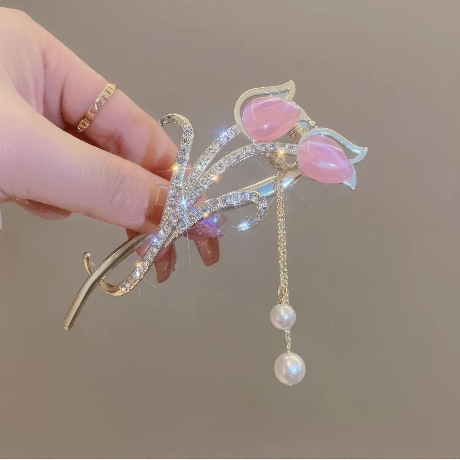 Hand holding pink cat - eye stone tulip tassel hair clip