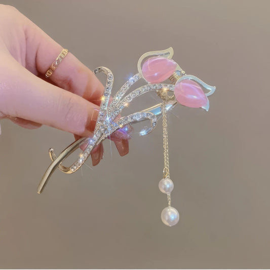Hand holding pink cat - eye stone tulip tassel hair clip