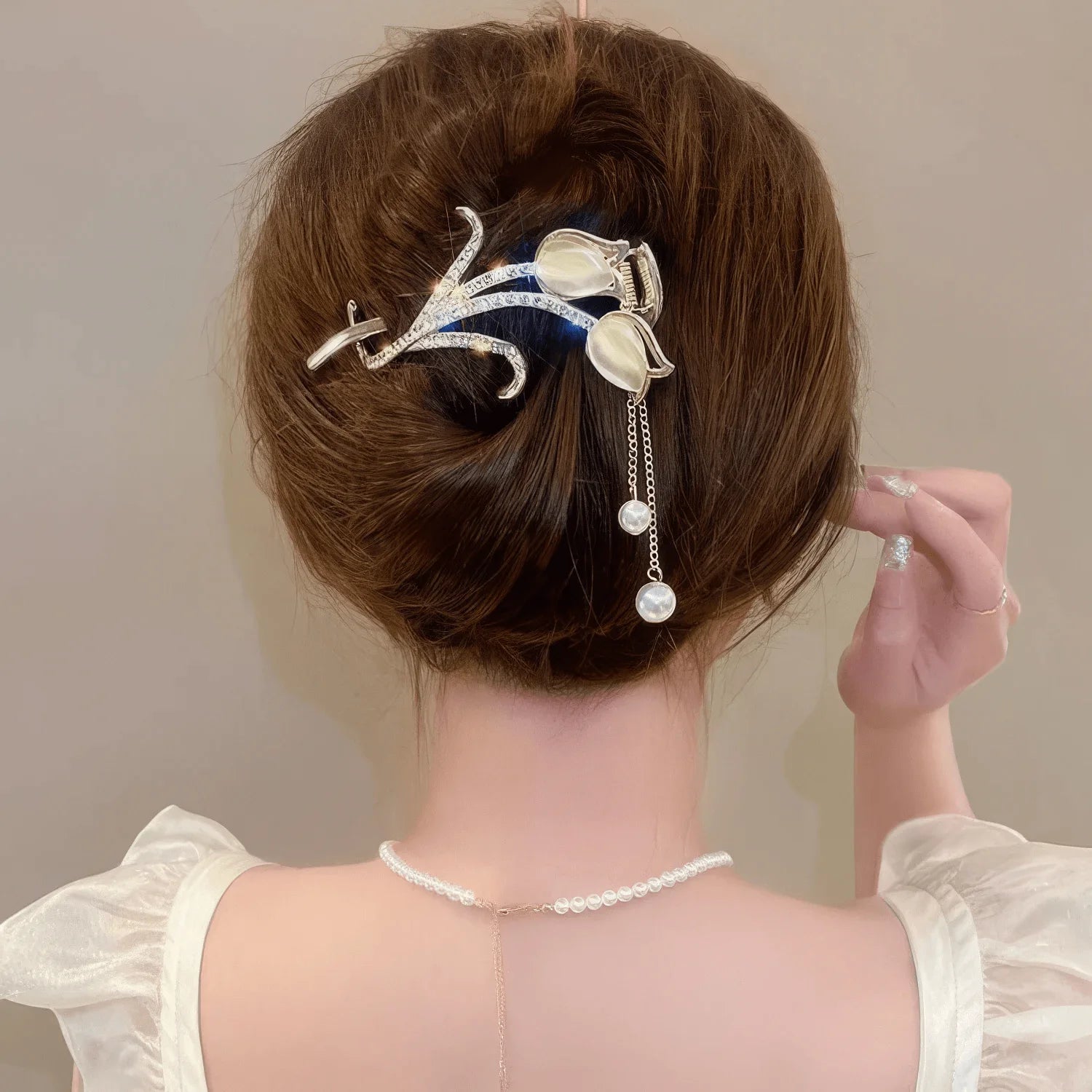 White cat - eye stone tulip tassel hair clip worn on an updo hairstyle