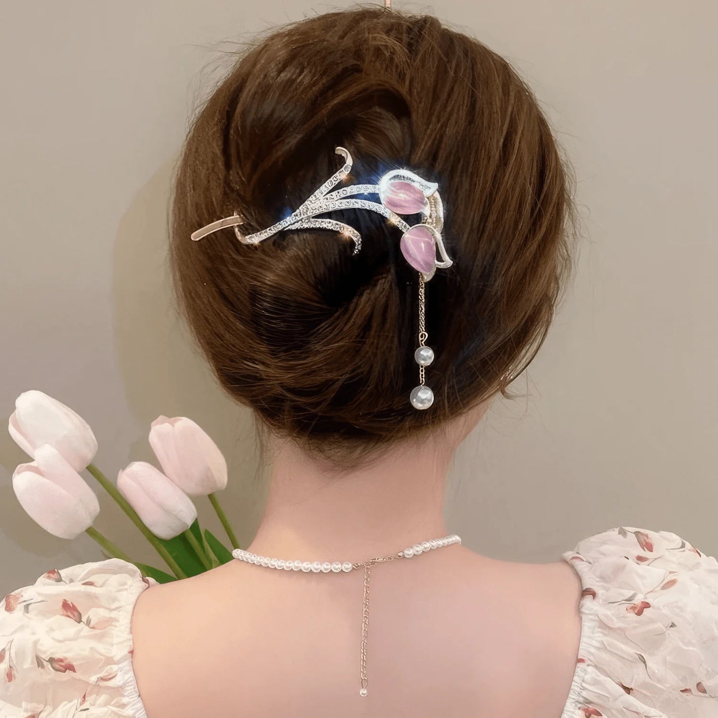 Another view of pink cat - eye stone tulip tassel hair clip worn on an updo hairstyle with tulips in background