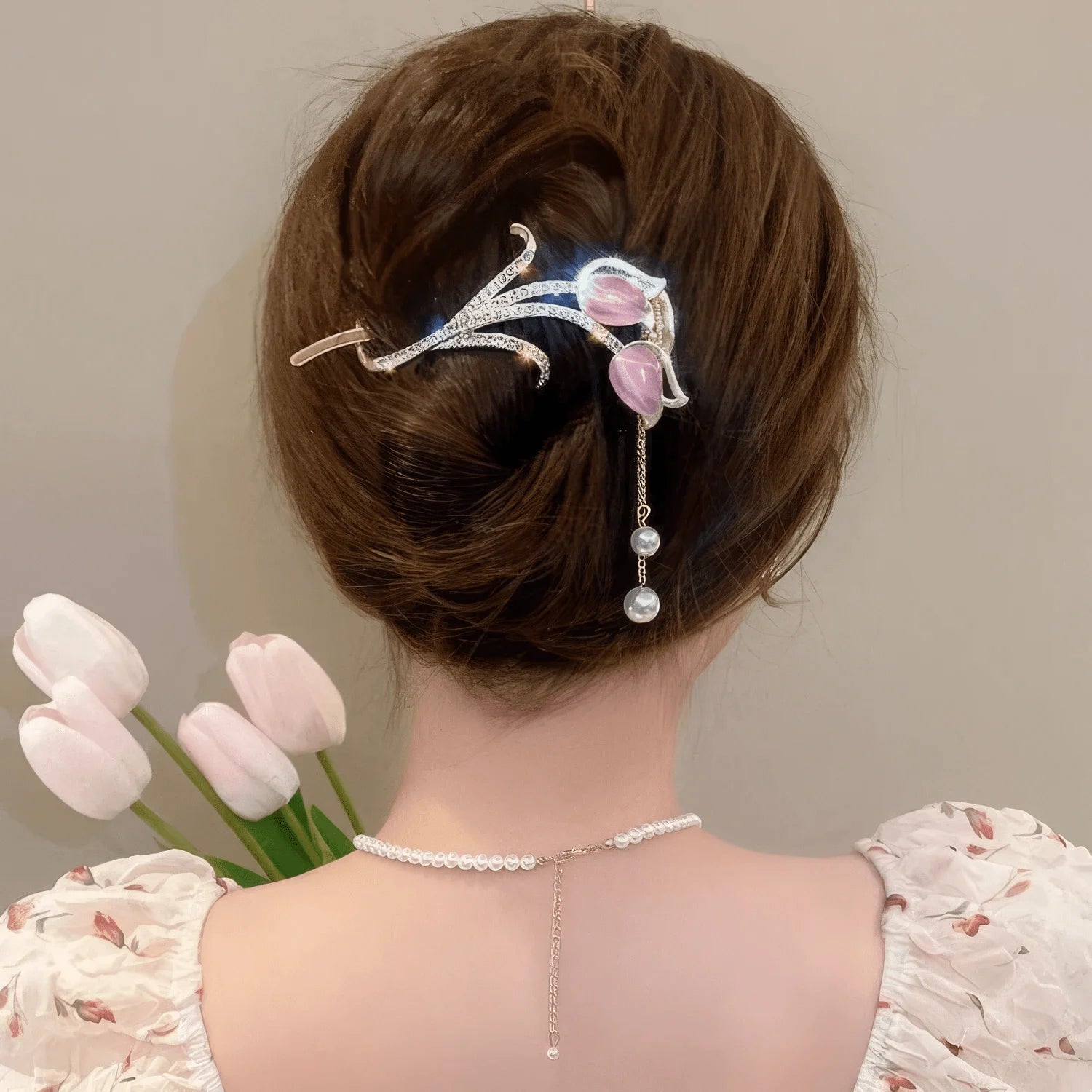 Another view of pink cat - eye stone tulip tassel hair clip worn on an updo hairstyle with tulips in background