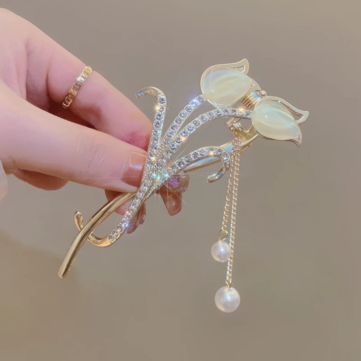 Another view of hand holding white cat - eye stone tulip tassel hair clip