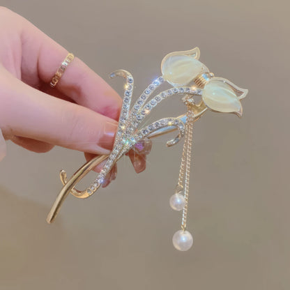 Another view of hand holding white cat - eye stone tulip tassel hair clip
