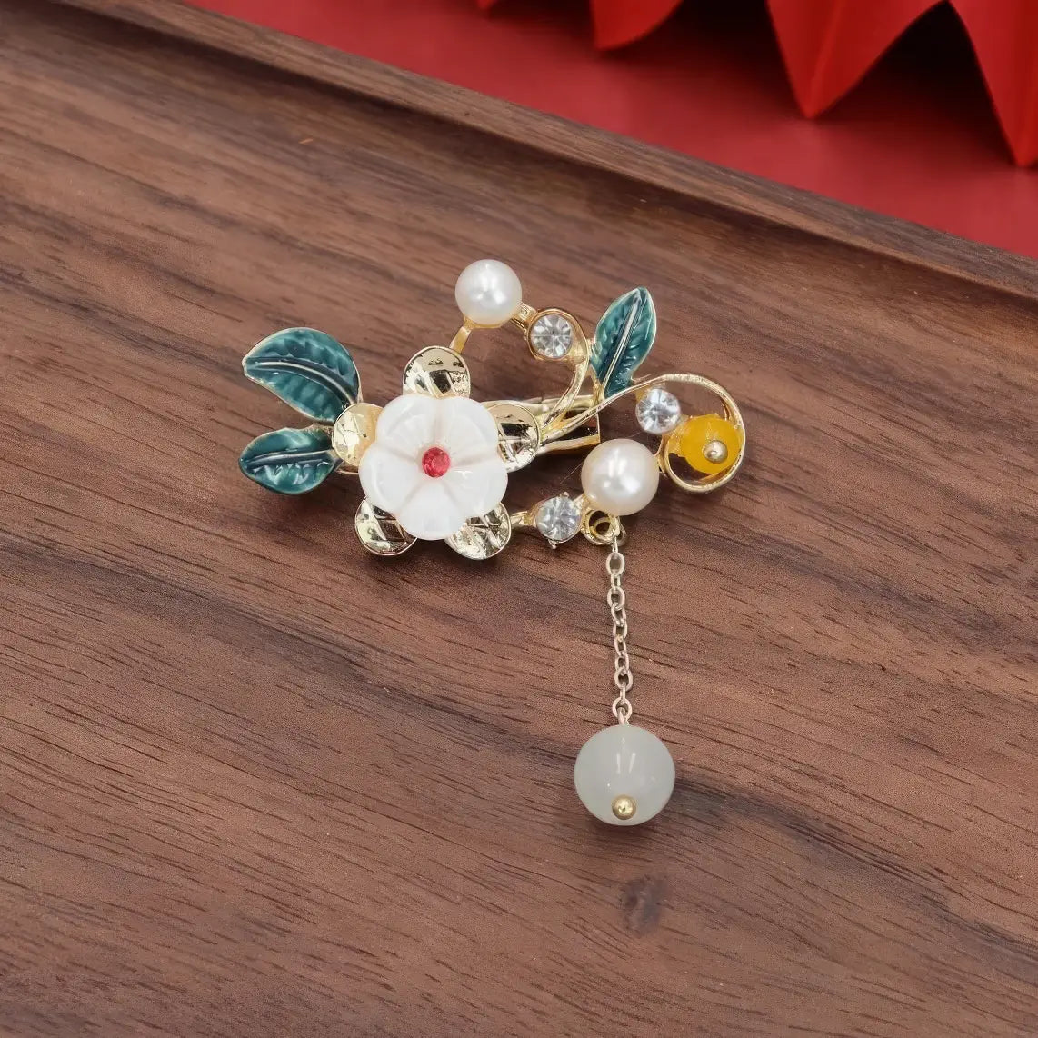 Chinese - style flower tassel brooch with multiple flowers and beads, on wooden background