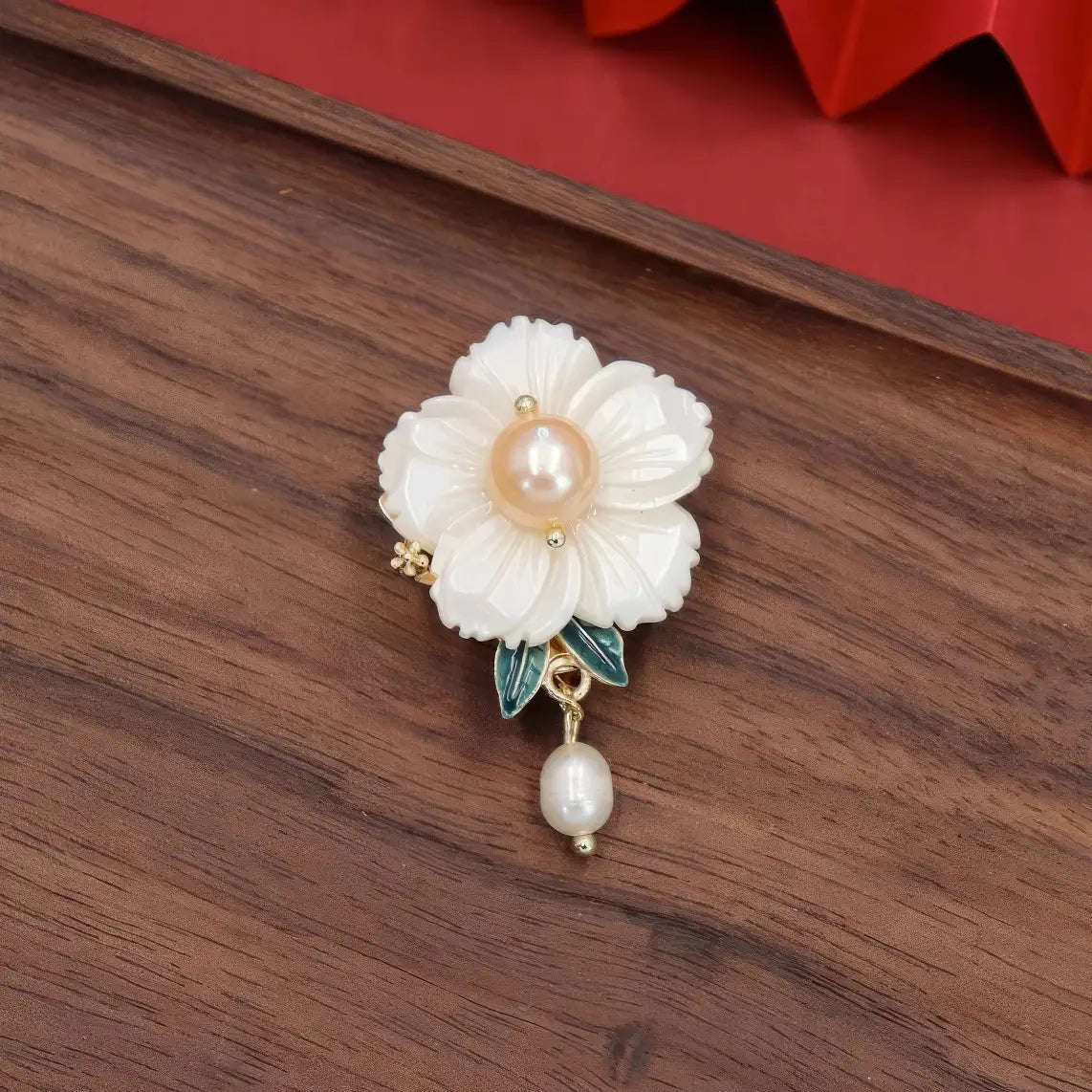 Single white flower Chinese - style brooch with pearl, on wooden background