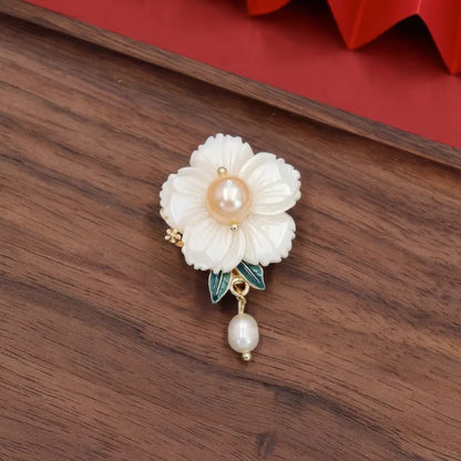 Single white flower Chinese - style brooch with pearl, on wooden background