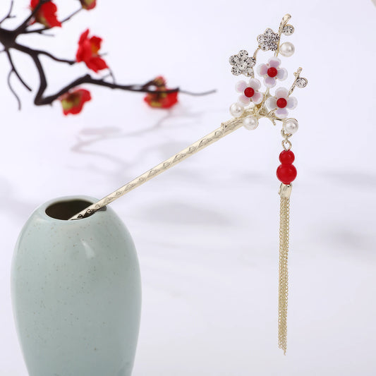 Chunhuayin hairpin featuring red beads, floral design and gold tassel, in light green vase