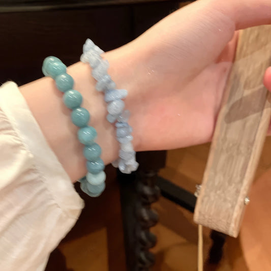 Hands wearing cloud - mountain neo - Chinese beaded bracelets, holding a wooden board, light background