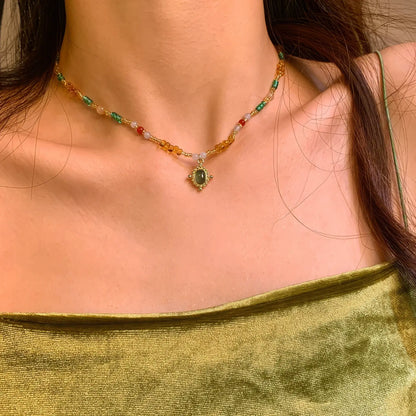 Colorful beaded pendant necklace worn, paired with a green garment, highlighting the necklace's colors