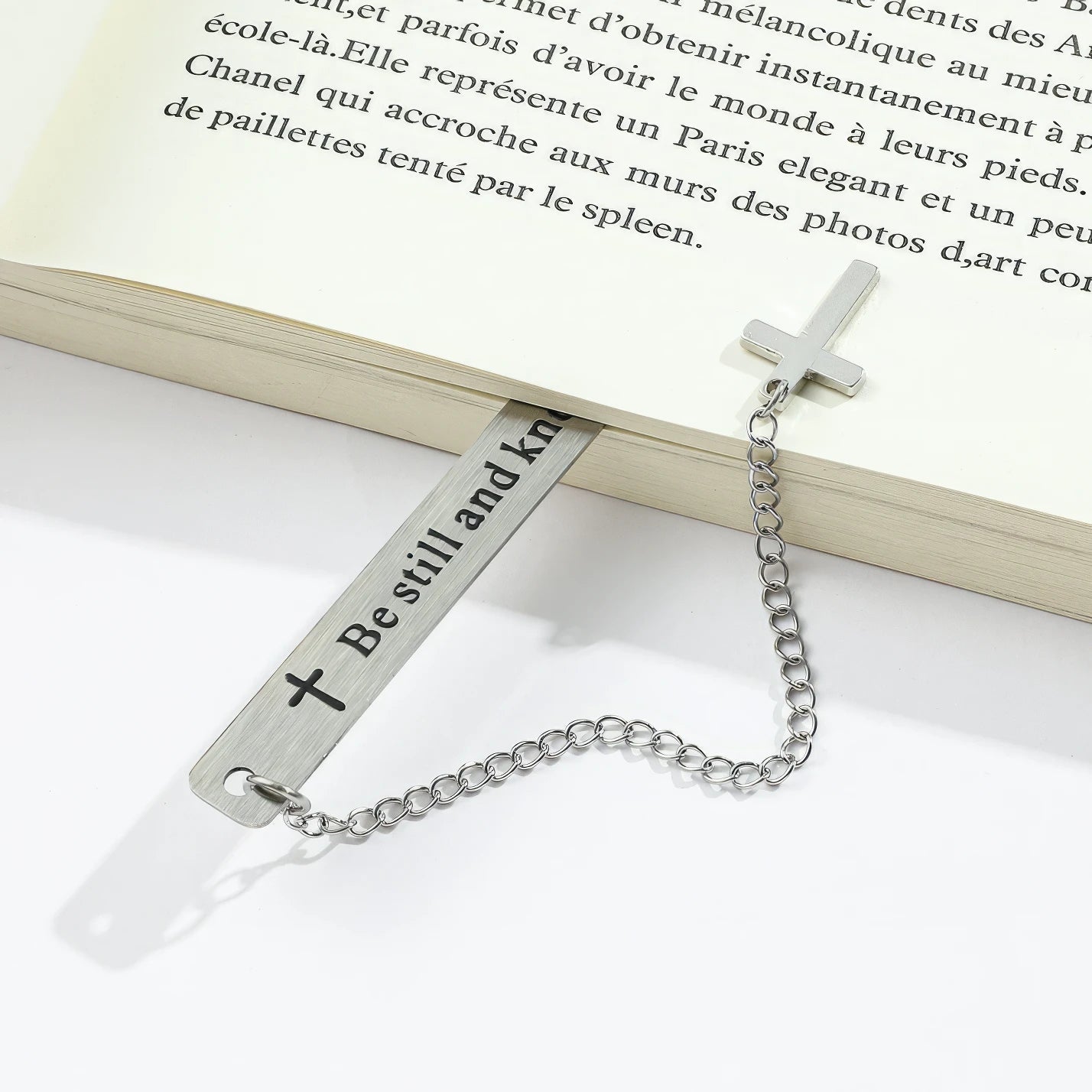 Cross metal bookmark placed in open book, light background