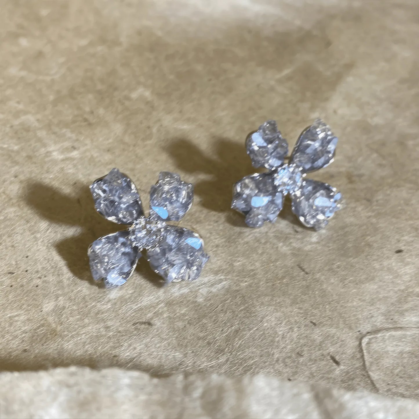 Crystal flower earrings, clear style, displayed on beige pad