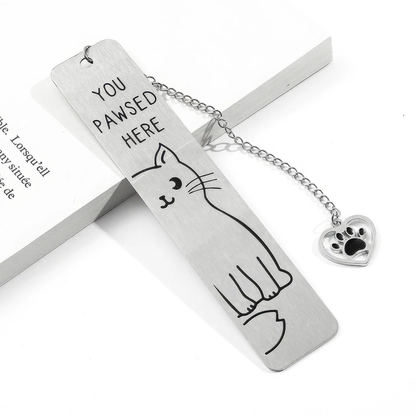 Cute cat stainless steel bookmark with chain and paw charm, displayed on book, white background