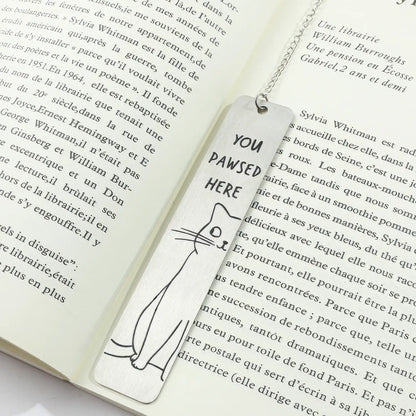 Cute cat stainless steel bookmark with chain and paw charm, placed in open book, white background