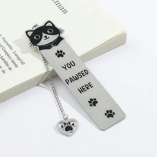 Cute cat stainless steel bookmark with chain and paw charm, placed in open book, white background