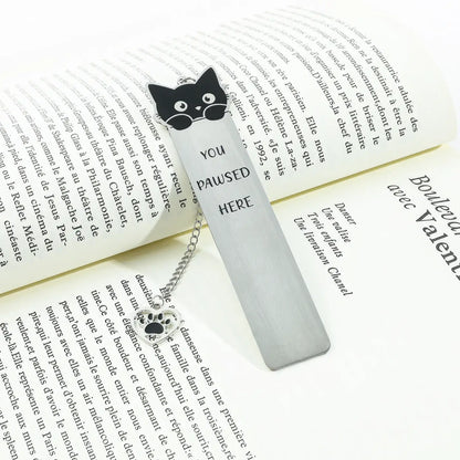 Cute cat stainless steel bookmark with chain and paw charm, placed in open book, white background
