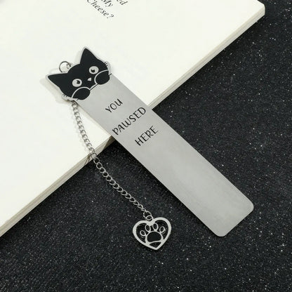 Cute cat stainless steel bookmark with chain and paw charm, displayed on black surface, white background