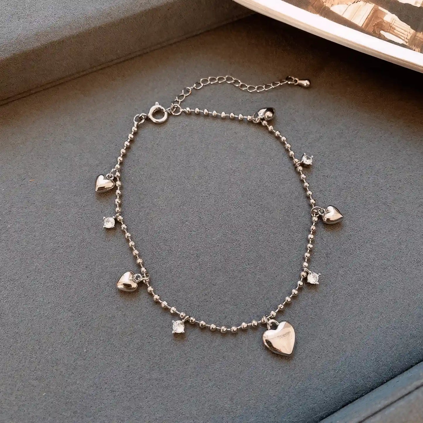 Dangling heart diamond bracelet, silver - tone, isolated on gray background