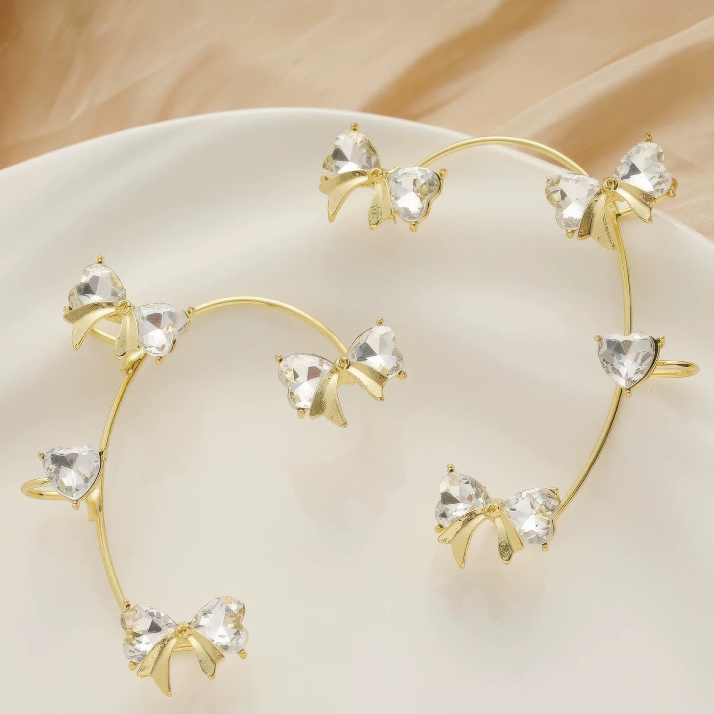 Gold diamond butterfly ear cuff, placed on white plate, delicate butterfly arrangement